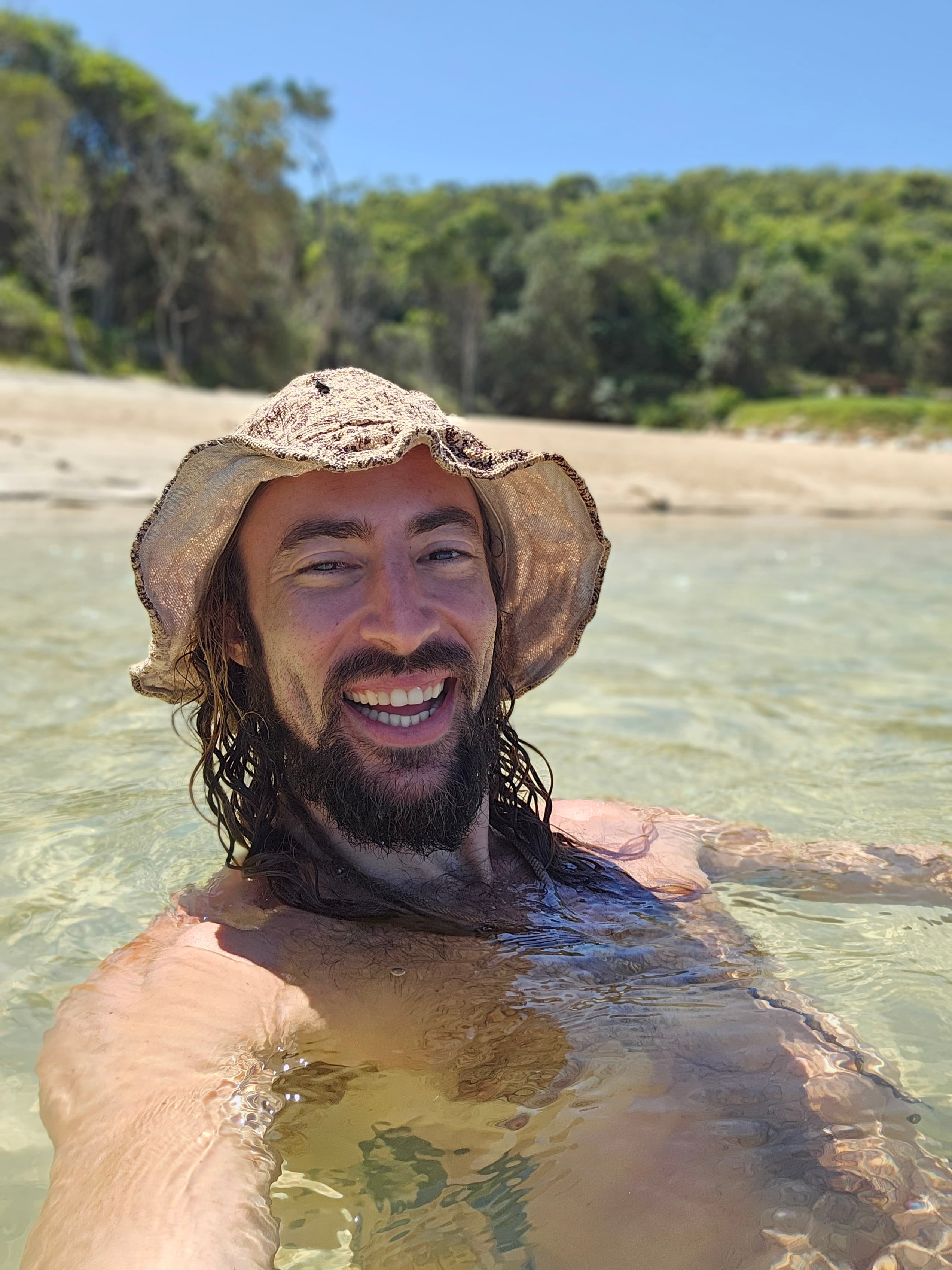 Ben smiling in clear water at the beach